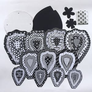 May include: A set of black and white patterned paper cutouts in the shape of hearts, flowers, and a circle. The cutouts are designed for crafting and decorating.