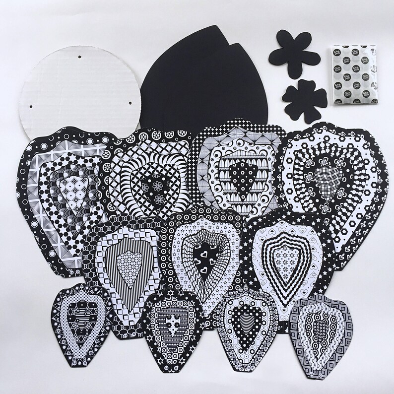 May include: A set of black and white patterned paper cutouts in the shape of hearts, flowers, and a circle. The cutouts are designed for crafting and decorating.