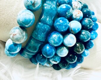 May include: A collection of blue beaded bracelets. The bracelets feature a variety of round beads in shades of blue, with some beads showing a marbled effect. A carved blue stone bracelet is also included.