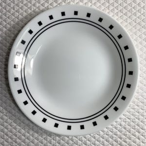 May include: A white plate with a black square and line design around the rim. The plate has a simple, clean aesthetic, suitable for everyday use. The plate is round and appears to be made of ceramic or a similar material.