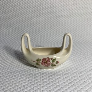 Vintage pottery vase features a floral design.