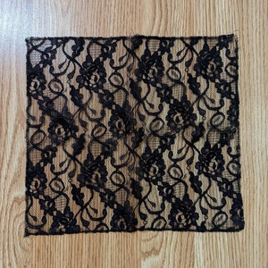 May include: Black lace fabric with a floral pattern. The fabric is delicate and has a soft texture.