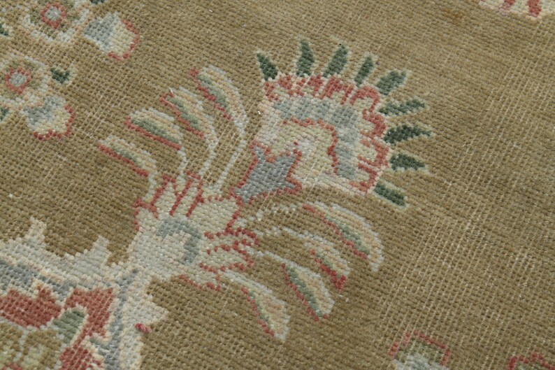 May include: Close-up of a beige rug with a floral pattern. The rug features a design of stylized flowers in shades of pink, green, and blue.