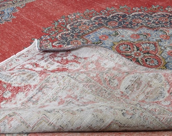 May include: A red and white rug with a floral pattern. The rug is folded in half, showing the back side.