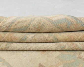 May include: A folded beige rug with a light blue geometric pattern. The rug has a soft, textured surface.