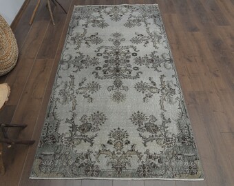 May include: A vintage-style rug with a gray background and a floral pattern in shades of gray and brown. The rug has a distressed look and is perfect for adding a touch of vintage charm to any room.