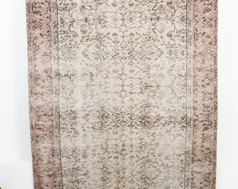 May include: A rectangular area rug featuring a faded dusty rose and beige background with a repeating black floral and vine pattern. The rug has a wide decorative border with intricate black botanical motifs framing the central design.