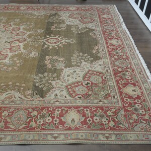 May include: A vintage rug with a floral pattern in shades of red, green, and beige. The rug has a fringed edge and a central medallion design.
