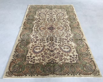 Könnte beinhalten: Ein cremefarbener Teppich mit einem detaillierten Blumenmuster in Braun-, Grün- und Beigetönen. Der Teppich hat einen Paisley-Rand.