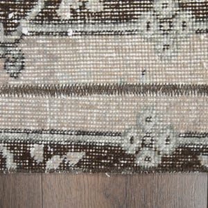 May include: Close-up of a brown and white patterned rug with a fringe border. The rug has a distressed look and is made of woven fibers.