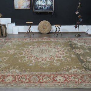 May include: A large, intricately patterned rug with a beige background and a central medallion in shades of cream, red, and green. The rug has a red and cream border with floral motifs.