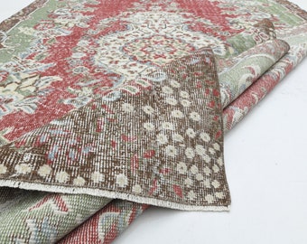 May include: A red, green and brown patterned rug with a floral design. The rug is folded in half and the edges are visible.
