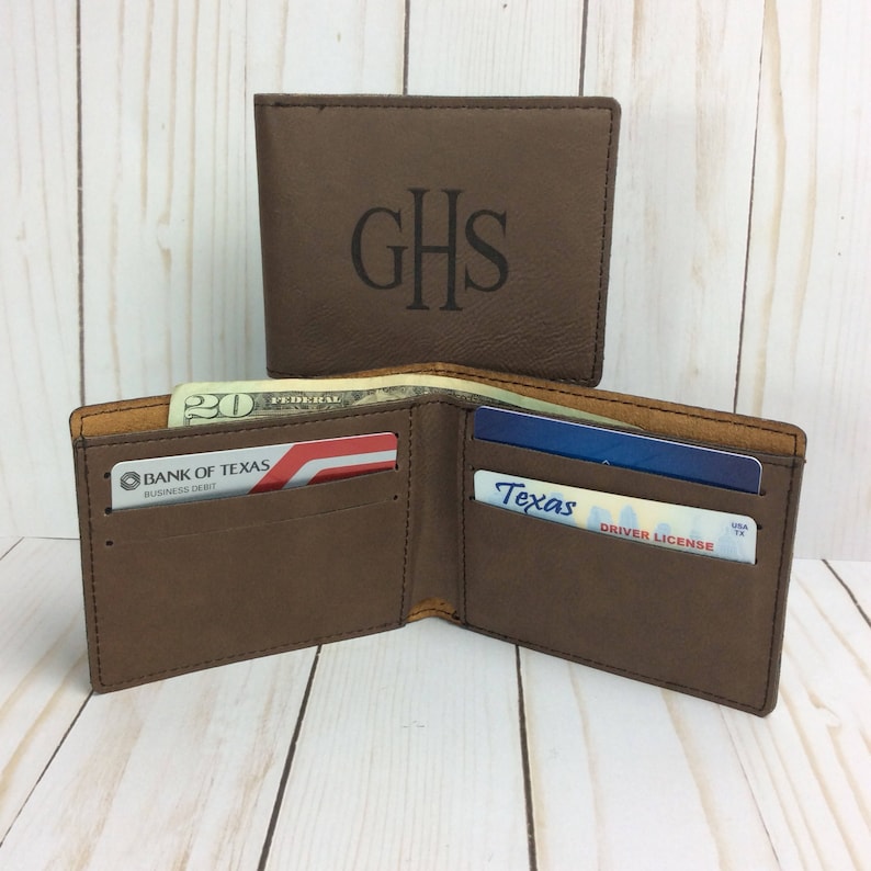 May include: A brown leather wallet with a monogrammed "GHS" on the front. The wallet is open and shows a credit card, a driver's license, and cash.