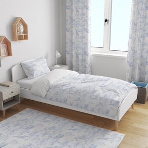 Puede incluir: Una cama blanca con una colcha, almohada y cortinas estampadas en azul y blanco. Una alfombra azul claro con el mismo estampado está en el suelo. Estanterías de madera y una mesita de noche completan la decoración del dormitorio.