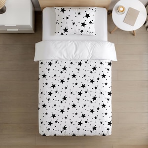 May include: White bedding set featuring a black star design. The set comprises a duvet cover and a pillowcase. The stars are of varying sizes and are spread across the white surface. The bedding is neatly arranged on a bed.