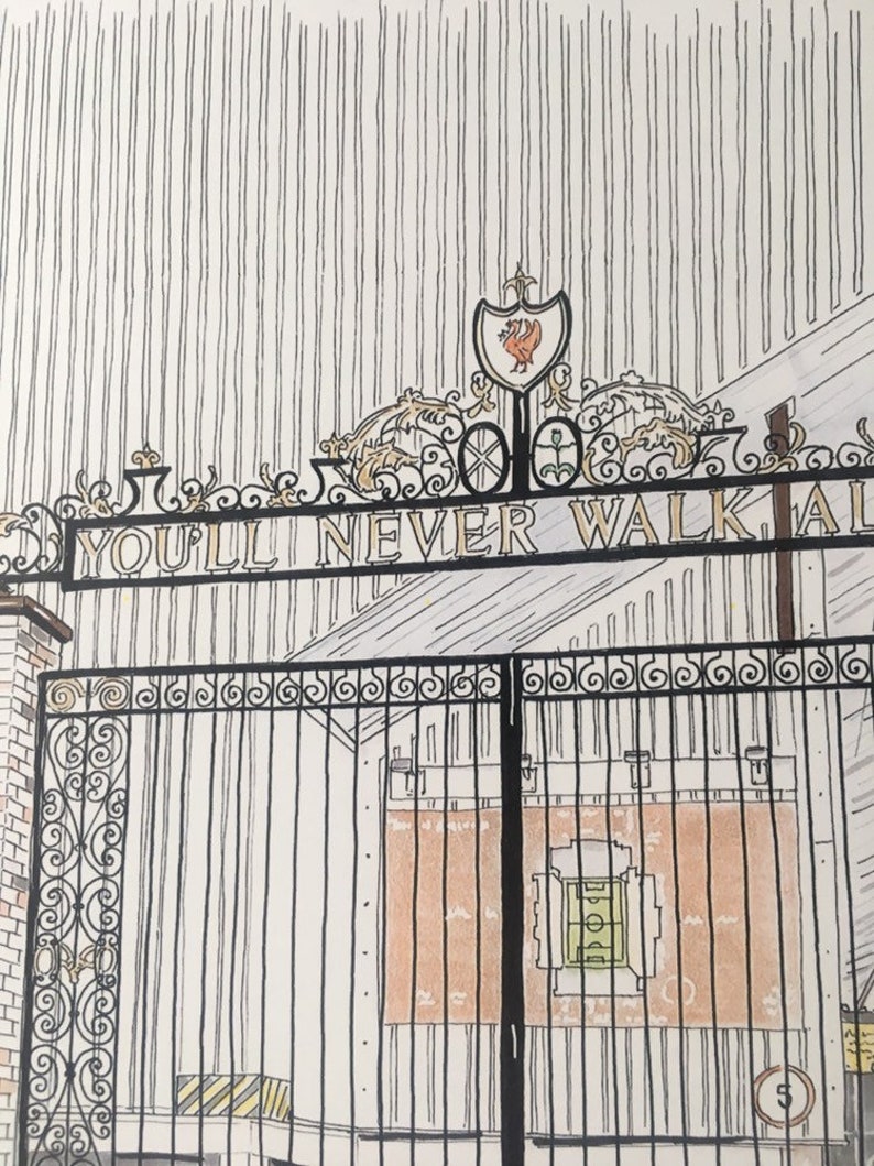 May include: A black metal gate with intricate scrollwork and the words "You'll Never Walk Alone" inscribed on it. The gate is closed and behind it is a brick building with a red and green soccer field.