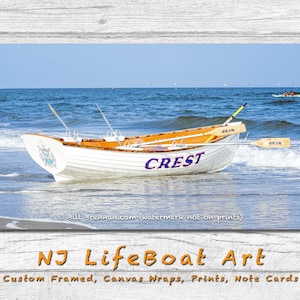 K&ouml;nnte beinhalten: Ein wei&szlig;es und orangefarbenes Holzboot mit der Aufschrift "CREST" liegt an einem Sandstrand mit Meereswellen. Das Boot hat Ruder und ein Kompassdesign. Das Bild ist ein Druck von NJ LifeBoat Art.