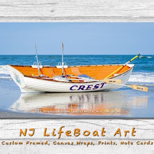 May include: A white and orange lifeboat, labeled "CREST", rests on a sandy beach with the ocean in the background. Two oars and two tall poles are visible. The image is a print of NJ LifeBoat Art.