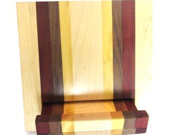 May include: A wooden chopping board with a built-in drawer. The board is made from different types of wood, including maple, walnut, and cherry. The drawer is also made of wood and has a natural finish.