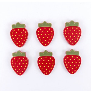 May include: Six red wooden strawberry buttons with green leaves and yellow seeds.