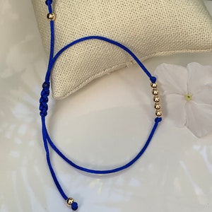 Bead ball blue  string bracelet im 14k Yellow Gold.