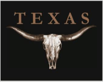 May include: A black and white image of a longhorn skull with large horns against a black background. The word "TEXAS" is written in a serif font above the skull.