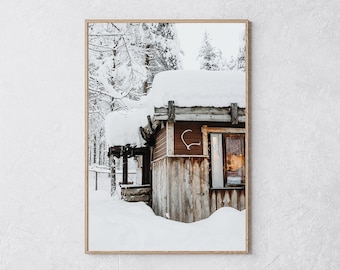 Könnte beinhalten: Gerahmtes Foto eines schneebedeckten Blockhauses in einem Winterwald. Das Blockhaus hat eine Holzfassade mit braunem Dach und Wänden. Ein dekoratives Herz hängt an der Seite des Blockhauses. Die Szene ist mit Schnee bedeckt.