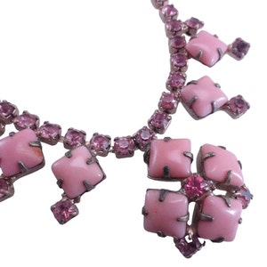 Op de afbeelding: Een roze strass ketting met een grote roze stenen hanger. De hanger bestaat uit vier vierkante stenen die in zilver zijn gezet.