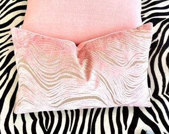 May include: A pink velvet cushion with a wavy, abstract pattern. The cushion is on a black and white zebra print fabric.