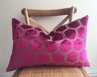 May include: A pink velvet cushion with a gold honeycomb pattern. The cushion is sitting on a wooden chair with a woven seat.