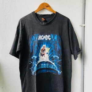 Pode incluir: Camiseta preta com um gráfico azul e branco de uma banda de rock, AC/DC, com o texto "Ballbreaker".