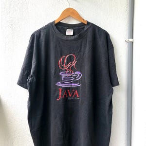 May include: Black t-shirt featuring a graphic of a coffee cup and the word "JAVA" in red and purple lettering. The text "http://java.sun.com" is printed below the word "JAVA".