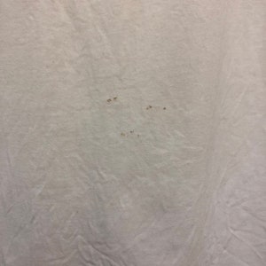 May include: White t-shirt with several small brown stains.