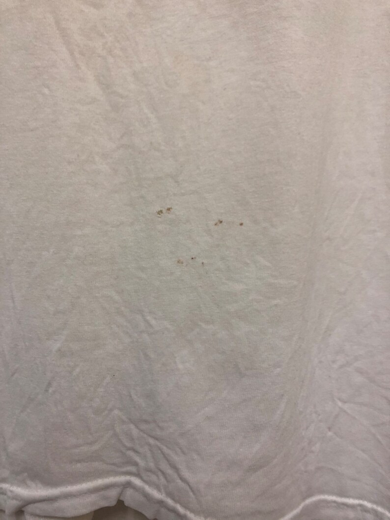 May include: White t-shirt with several small brown stains.