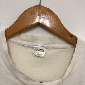 May include: White t-shirt with a white tag that says "scene" on it.
