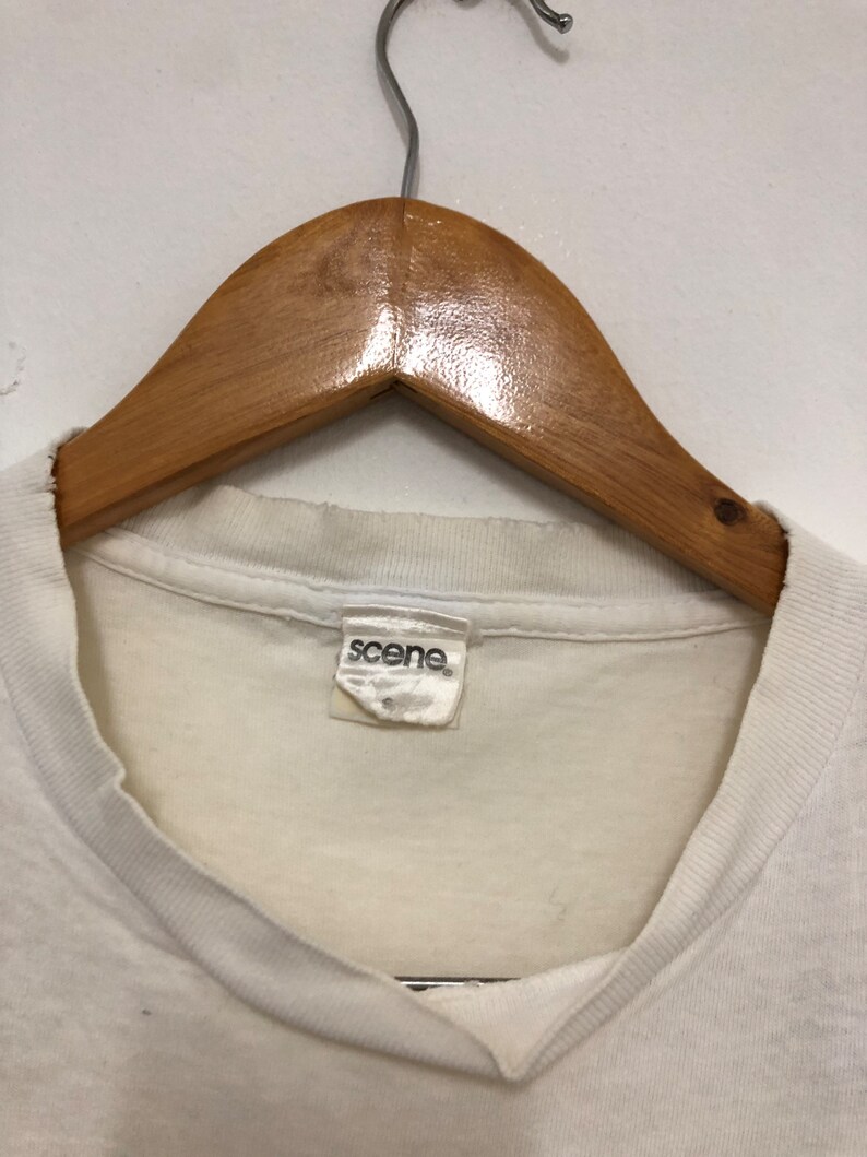 May include: White t-shirt with a white tag that says "scene" on it.