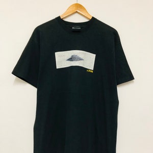 May include: Black t-shirt with a graphic of a flying saucer and the text "RECOGNIZE" in yellow.