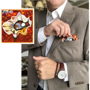 May include: A brown suit jacket with a pocket square featuring a colorful abstract design. The pocket square is being adjusted by a hand. A brown leather watch with a white face is on the wrist of the person wearing the jacket.