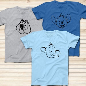 May include: Three t-shirts with different cartoon character designs. The first t-shirt is gray with a black and white cartoon owl. The second t-shirt is blue with a black and white cartoon pig. The third t-shirt is light blue with a black and white cartoon elephant.