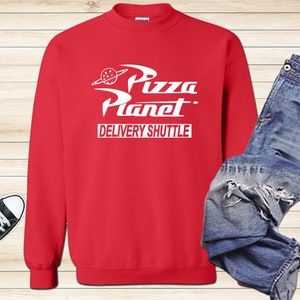 May include: Red sweatshirt with a white graphic of the Pizza Planet logo and the text "Delivery Shuttle".