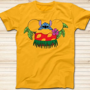 May include: Mustard yellow t-shirt featuring a cartoon graphic of Stitch from Lilo & Stitch. The design includes Stitch peeking out from behind a Mickey Mouse ear-shaped design with a red and yellow Hawaiian skirt, green palm leaves, and a pink hibiscus flower.