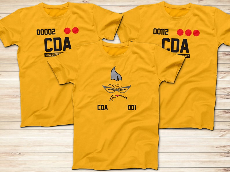 May include: Three yellow t-shirts with black text and red dots. The front of the shirts say "CDA" and have numbers. One shirt has a cartoon face with glasses and the text "CDA 001".