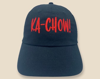 May include: A black baseball cap with red embroidered text that reads "KA-CHOW!"