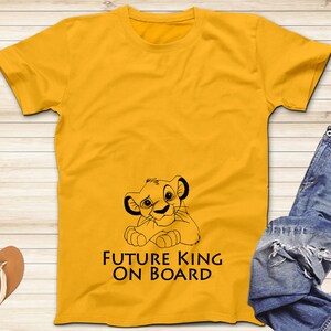 May include: Yellow t-shirt with a black outline of Simba from The Lion King. The text "Future King On Board" is printed on the shirt.