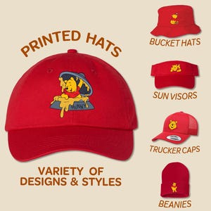 May include: A variety of printed hats featuring a Winnie the Pooh design. The hats include bucket hats, sun visors, trucker caps, and beanies. The text "PRINTED HATS" and "VARIETY OF DESIGNS & STYLES" is displayed on the image.