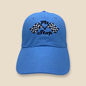 May include: A light blue baseball cap with a black and white checkered flag design and the text "Pit Stop" embroidered on the front.