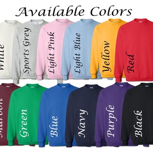 May include: A selection of 12 crewneck sweatshirts in various colors, including white, sports grey, light pink, light blue, yellow, red, maroon, green, blue, navy, purple, and black. Each sweatshirt has the color name printed on the side.