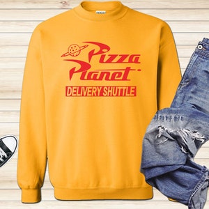 May include: Yellow sweatshirt with a red "Pizza Planet" logo and the words "Delivery Shuttle" printed on the front.