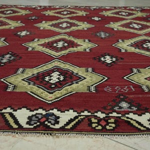 a close-up view of a vibrant, intricately patterned rug with a red background and a border of white and gold designs.