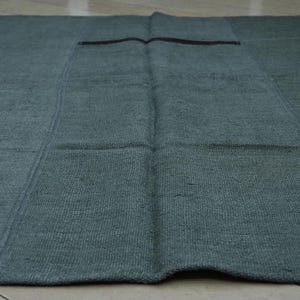 a close-up view of a dark green, textured rug or mat laid out on a wooden floor.